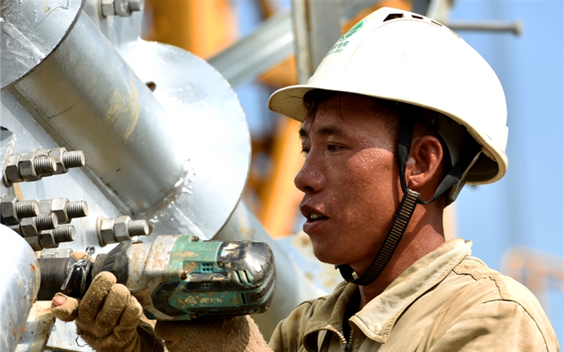 國網(wǎng)湖北送變電工程有限公司施工人員頭頂烈日，用電動扳手緊固螺栓。鄒小民攝