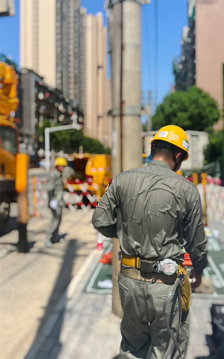 電力工作人員穿著特殊材質(zhì)的絕緣披肩，其厚度相當(dāng)于5件厚雨衣。王欣攝