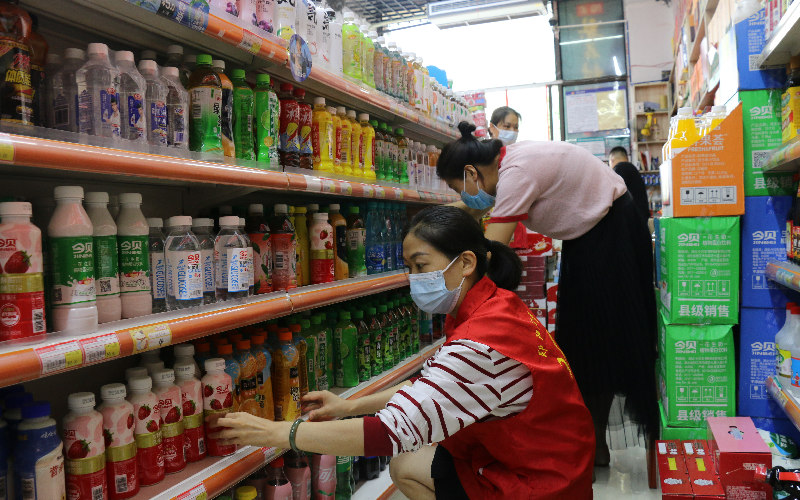 工作人員幫助店主整理貨架。