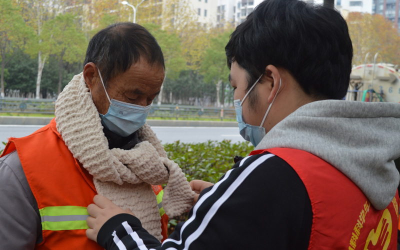 志愿者給環(huán)衛(wèi)工人戴圍巾。