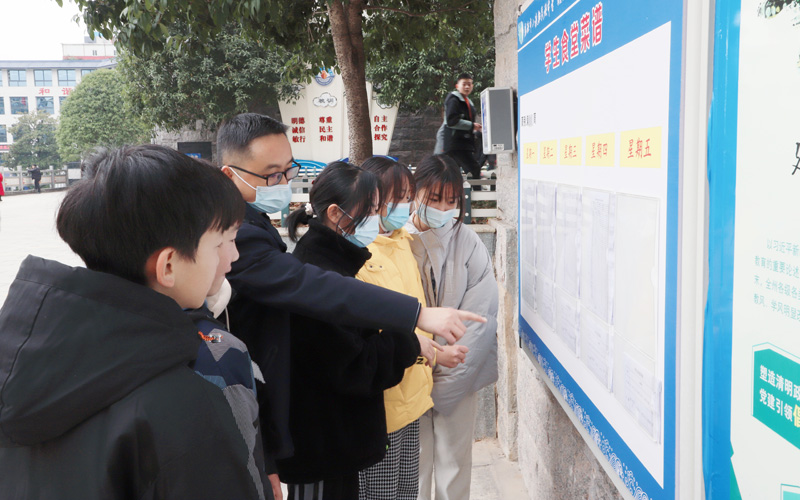 師生一起觀看學(xué)校食堂收支明細(xì)公示欄。