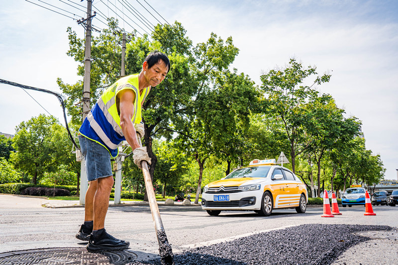 烈日下，武漢市市政維修人員對(duì)路面局部破損的位置鋪設(shè)瀝青混凝土面層。詹重山攝