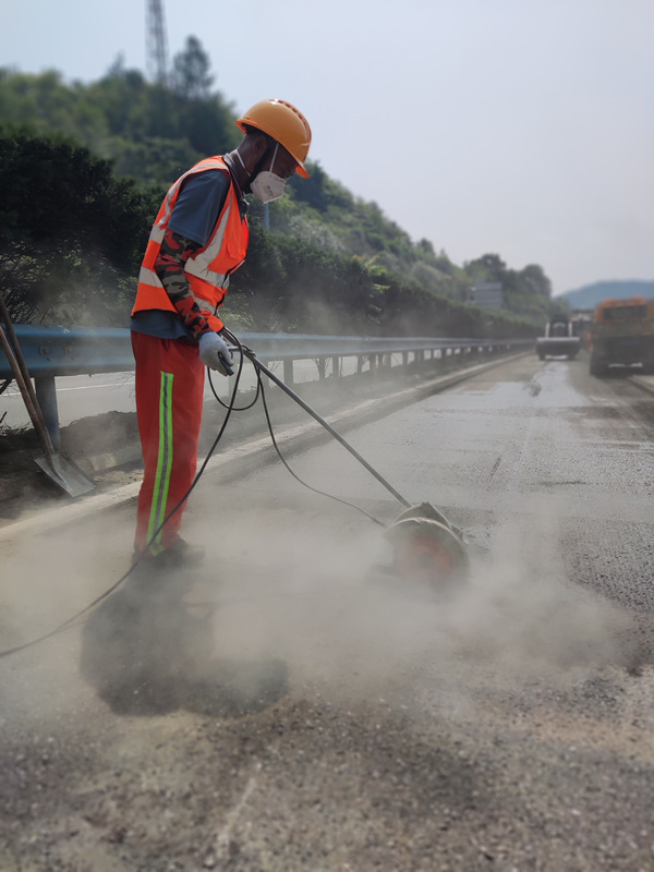 在福銀高速十土路段“集約化養(yǎng)護(hù)”施工現(xiàn)場，湖北交投鄂西北運(yùn)營公司施工人員冒著高溫切割路面坑槽。金偉忠攝