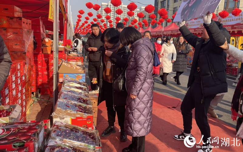 前來打年貨的市民在攤位前品嘗車厘子。人民網(wǎng)記者 周恬攝