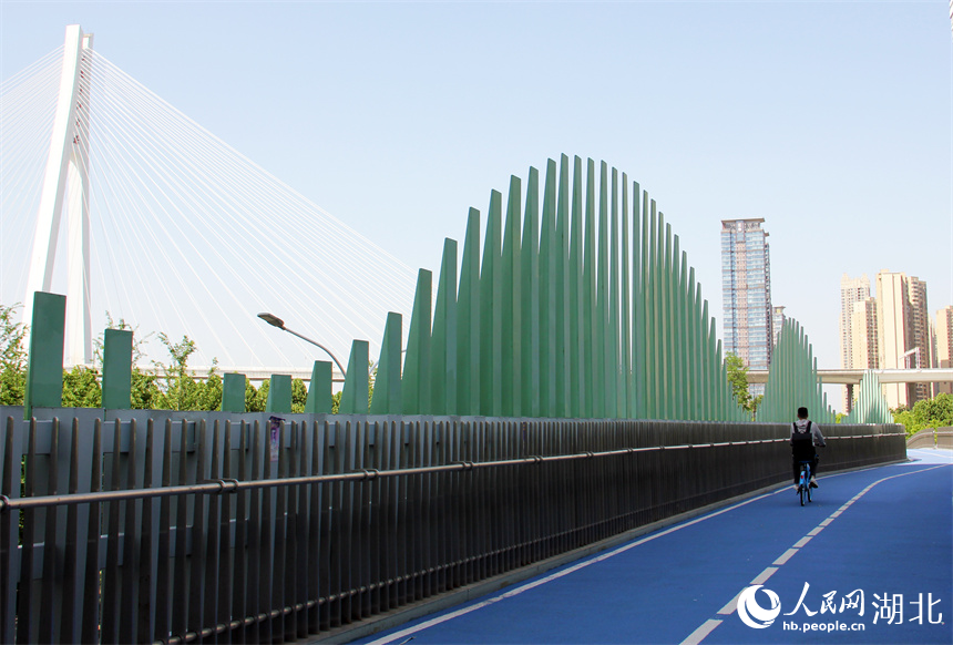 水波橋的造型創(chuàng)意來(lái)源于臨近的余家頭水廠(chǎng)。橋下車(chē)水馬龍，橋上是騎行慢生活。人民網(wǎng)記者 周恬攝