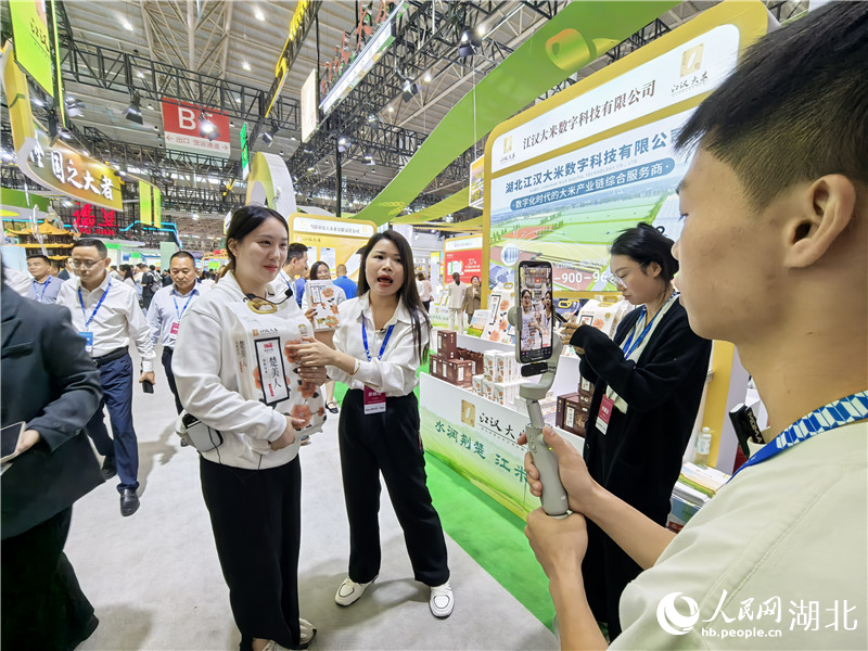 江漢大米展示區(qū)前，企業(yè)正在現(xiàn)場直播。人民網(wǎng)記者 周雯攝