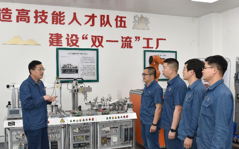 全國(guó)煙草行業(yè)技術(shù)能手、湖北省勞動(dòng)模范王志強(qiáng)（左）與青年員工交流傳授電控知識(shí)。汪鑫攝