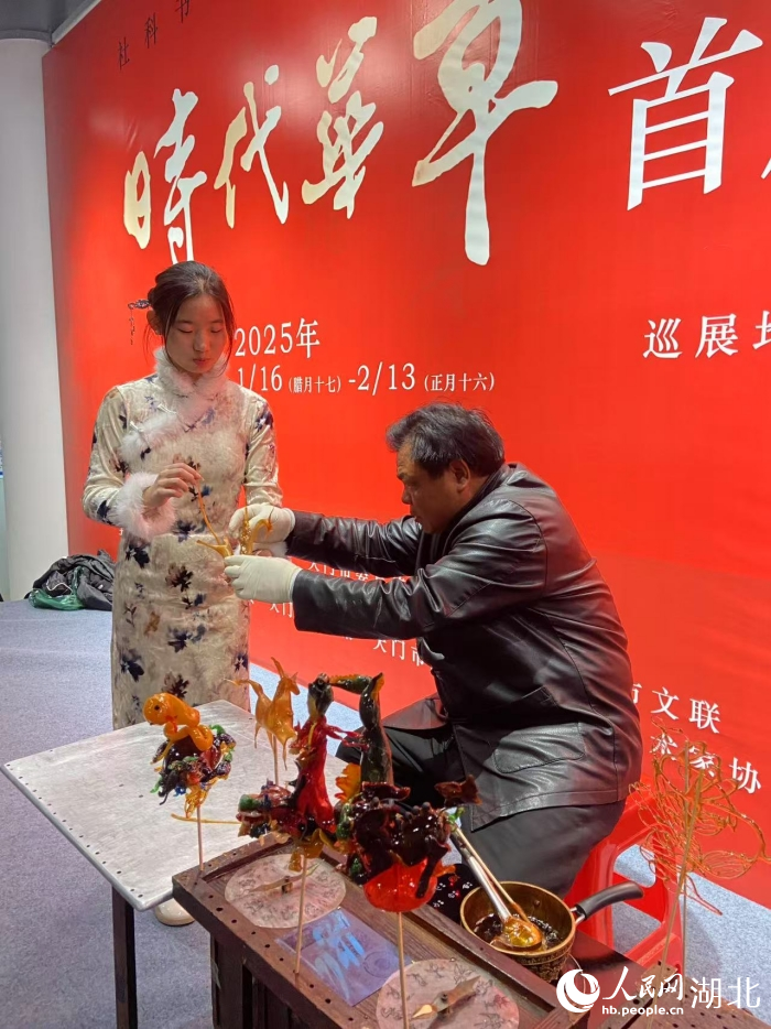 范耀堂在展會上和游客互動吹糖人。人民網(wǎng)記者 張雋攝