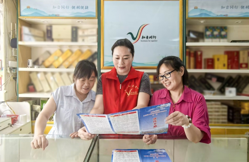 6月4日，十堰市鄖陽區(qū)煙草專賣局普法志愿者（中）到零售商店，通過入戶講解、發(fā)放普法手冊的方式開展普法宣傳。陳光霞攝