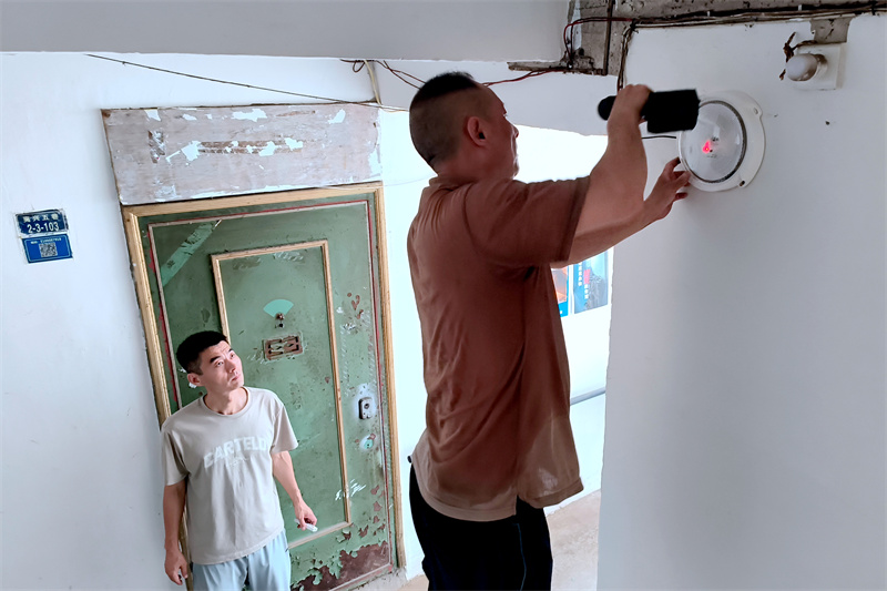 工作人員在樓梯口安裝太陽(yáng)能路燈