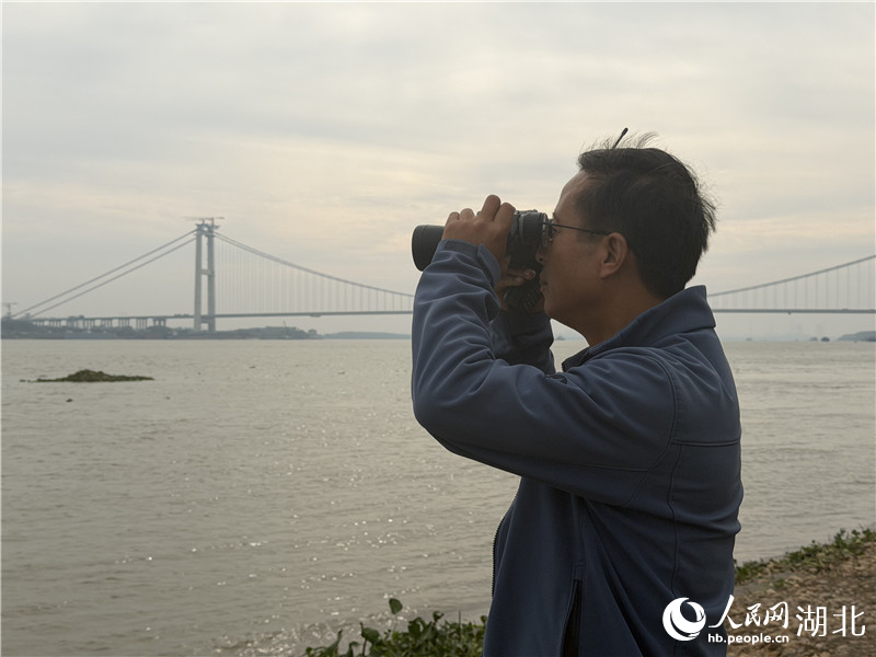 徐建利在江邊觀測江豚。人民網(wǎng)記者 張沛攝