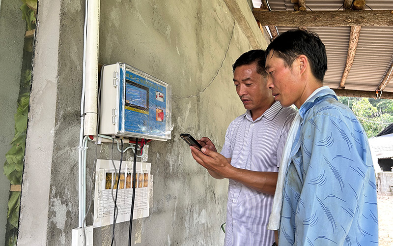 技術(shù)員指導(dǎo)煙農(nóng)在手機(jī)查看煙葉烘烤狀態(tài)。楊威攝